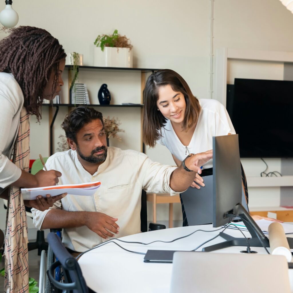 Diverse team engaged in collaborative discussion around computer in modern office.